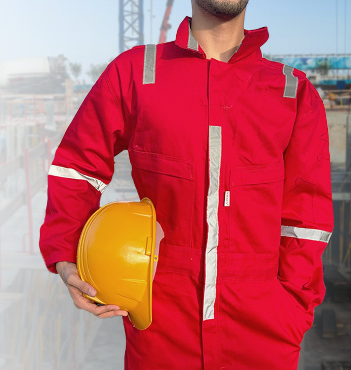 Trabajador con overol de seguridad rojo VMACS y casco, en obra